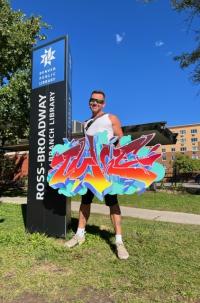 Tuke holds a piece of his artwork outside the Ross-Broadway Branch Library
