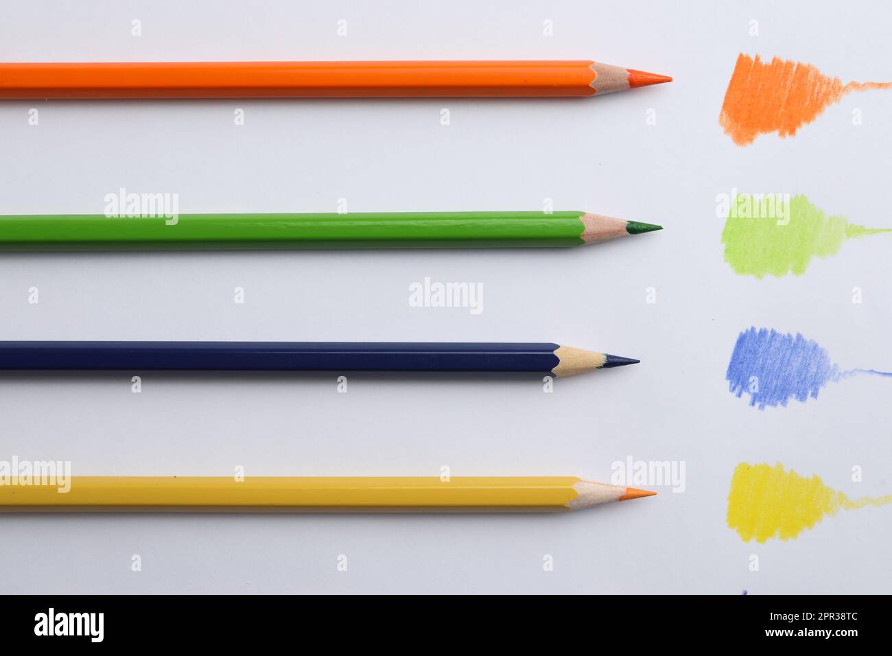 an orange, green, blue, and yellow pencil next to color swatches on white paper