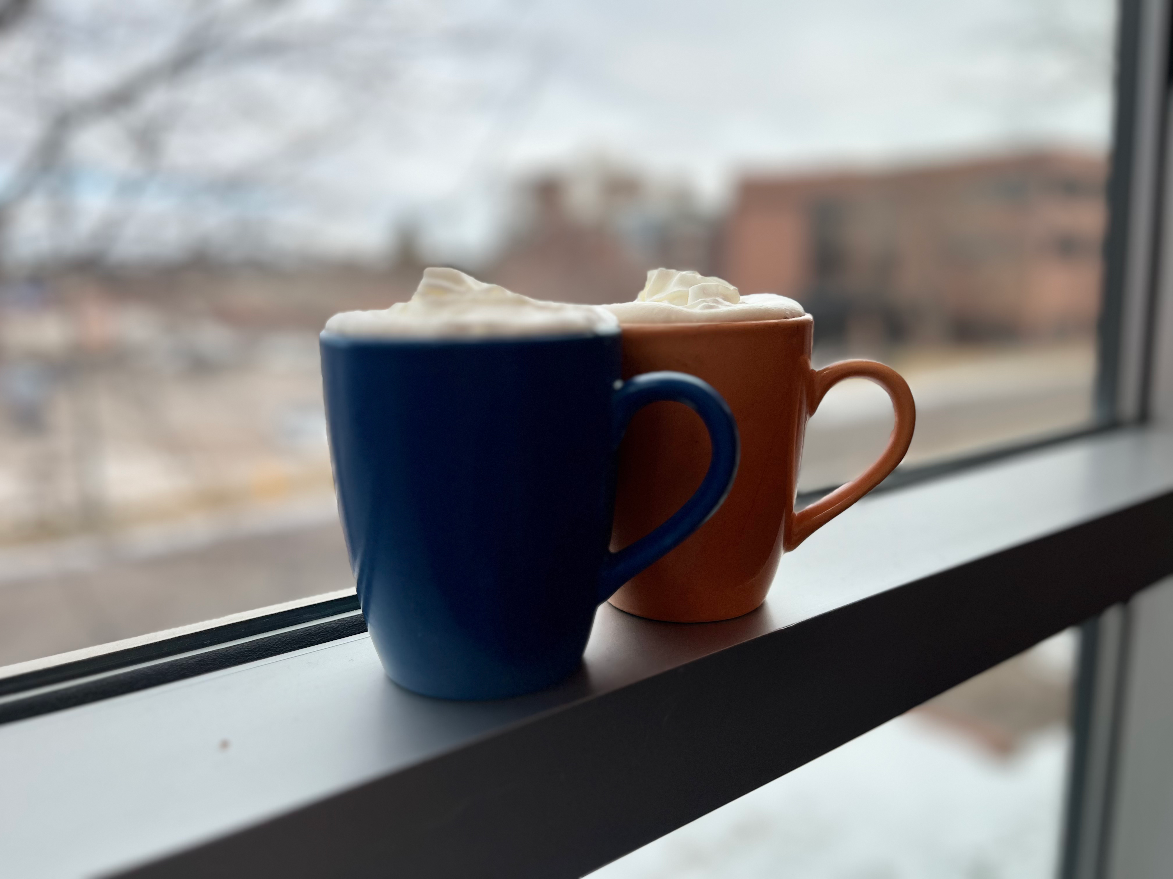 Photo of Hot Chocolate Affogatos on a window sill in a blue mug and an orange mug