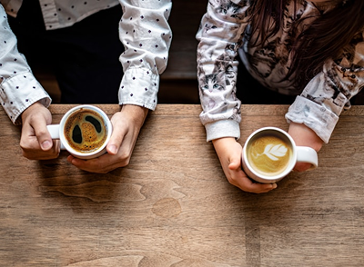 Two people sitting with coffee, aerial view.