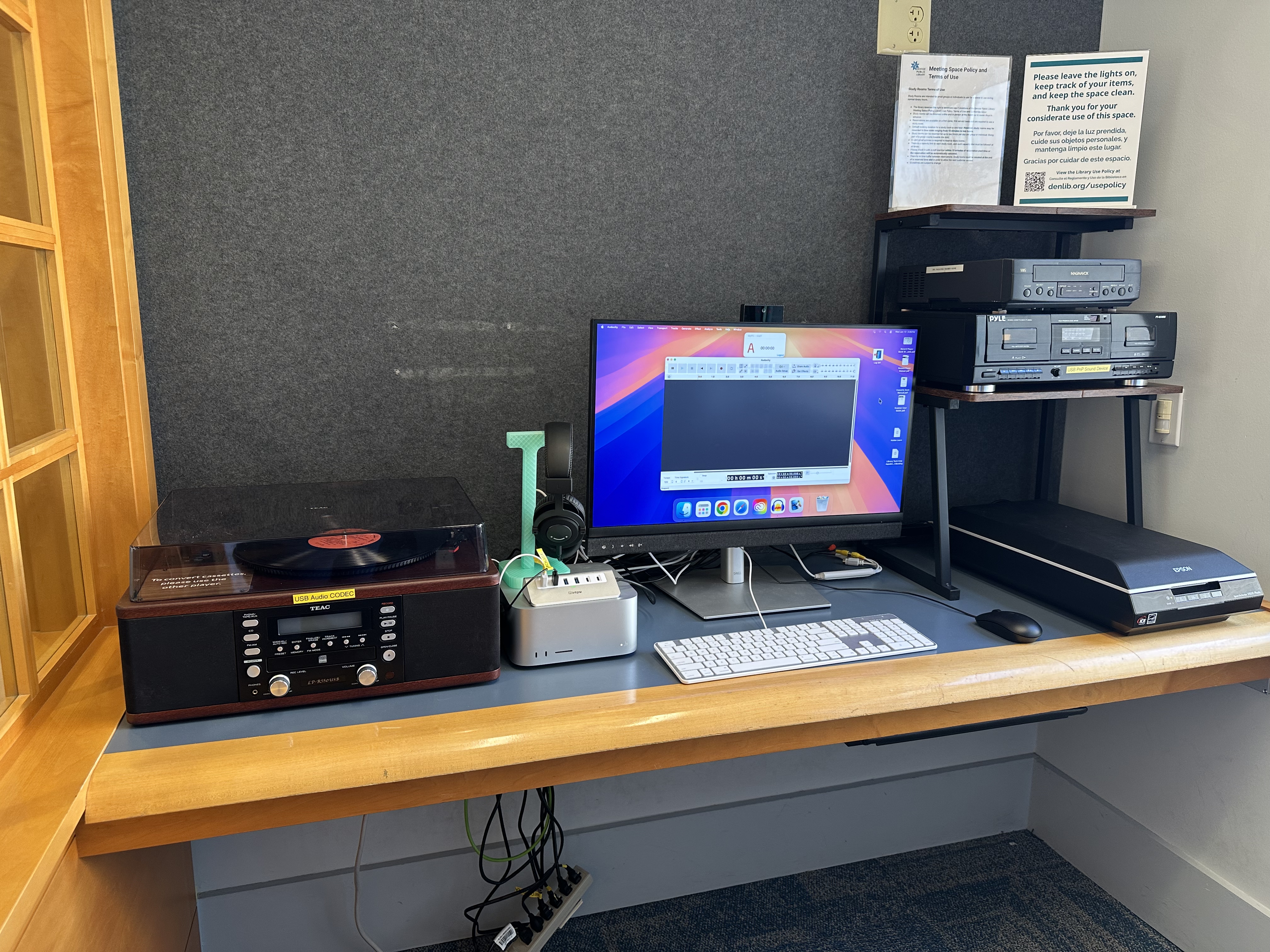 A media conversion workstation at the library featuring a computer, headphones, turntable, cassette deck, VHS/DVD player, scanner, and audio editing software for digitizing and editing media.