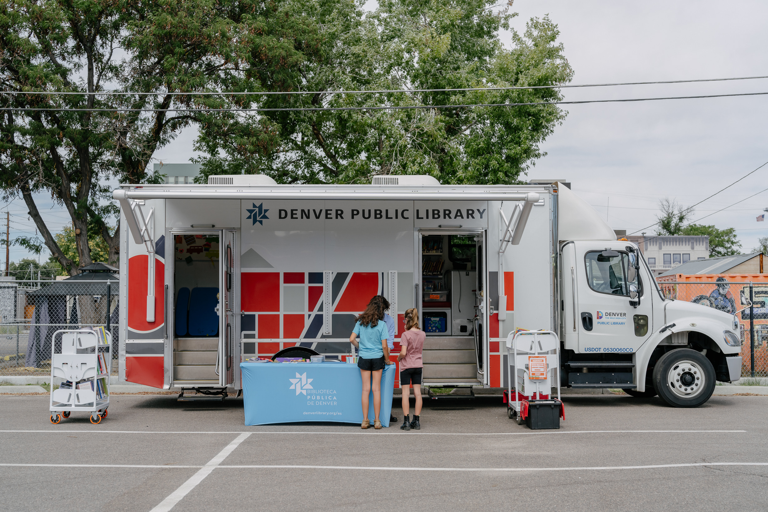 Two individuals checking out the Denver Public Library bookmobile at an outreach event. 