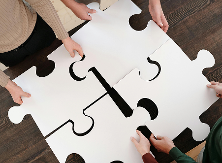 Top view of individuals bringing large puzzle pieces together