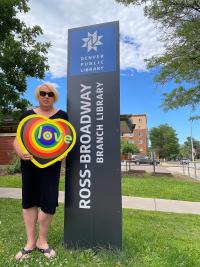 Koko Byer stands outside of the Ross-Broadway branch holding a piece of her art