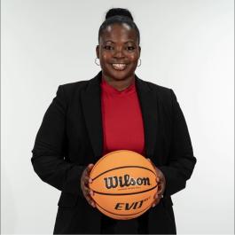 Picture of Doshia Woods, the Head Coach for the Women's Basketball team at the University of Denver. She is smiling and holding a basketball.