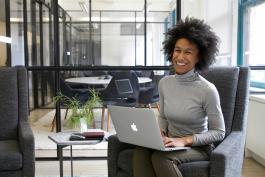 Woman in business attire sitting with laptop