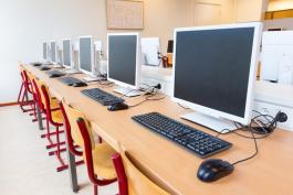 A row of computers with empty chairs, a computer lab