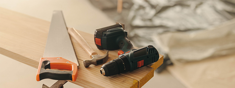 Hammer, drill gun, and crosscut saw on a table