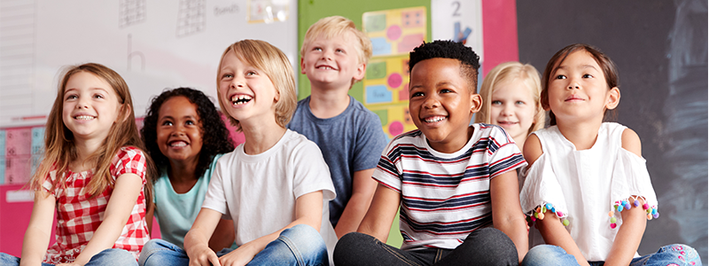 Group of elementary school students sitting on floor in classroom 
