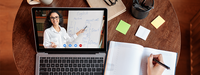 Overhead shot of student using laptop having online class with teacher